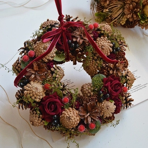 Vintage Christmas wreath with pine cones, red roses, berries and a velvet bow