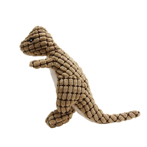 Close-up of brown textured fabric and embroidered eyes on the plush dinosaur dog toy