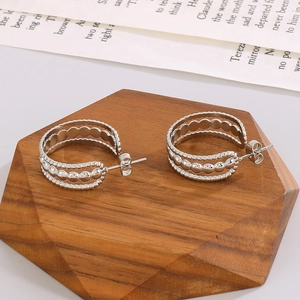 Détails de boucles d'oreilles argentées en forme de C avec texture tressée sur bois