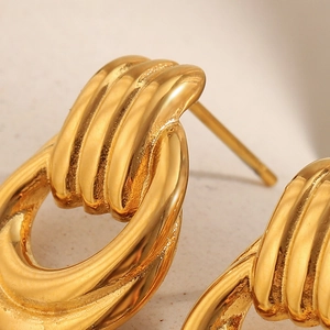 Detail of twisted 18K gold plated stainless steel hoop earring with polished finish