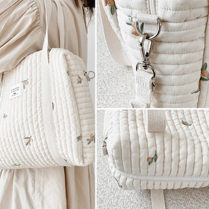Detail view of quilted cotton diaper bag with olive branch embroidery and metal hooks