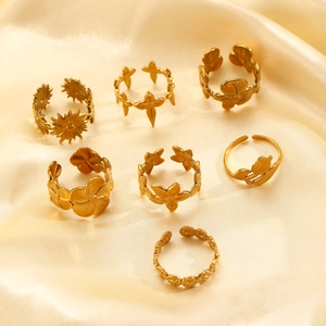 Detailed flat lay of adjustable gold stainless steel rings with floral motifs on silk