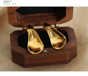 Macro shot of 18k gold plated geometric earrings in a luxury octagonal wood jewelry box