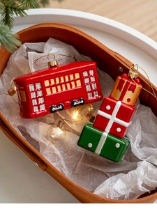 Close-up of vintage Christmas tree ornaments with red tram and colorful gift boxes