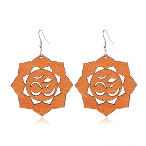 Detail of lotus flower wooden earrings featuring a hollow carved Om symbol with metal hooks