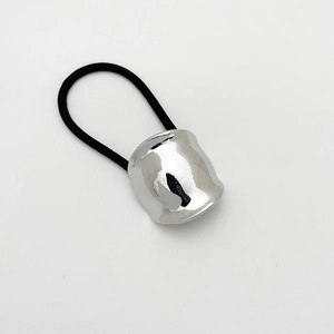 Detail of silver cylindrical metal buckle on a black elastic hair tie over white background