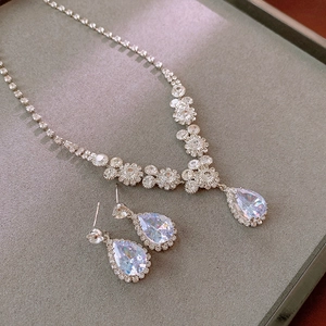 Dettaglio macro di parure con ciondolo a goccia in zircone argento su vassoio grigio