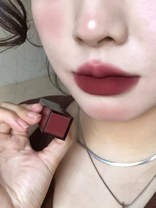 Close-up of matte dark red lip glaze applied on lips with product bottle display