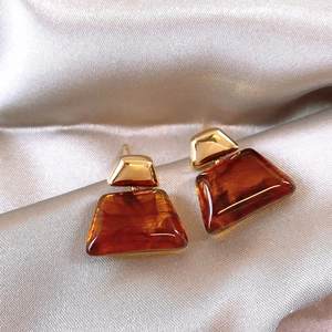 Detailed view of 18K gold plated geometric resin earrings on a silk background