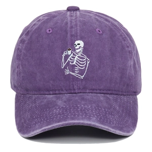 Détail de la broderie de crâne blanc sur une casquette de baseball vintage lavée violette