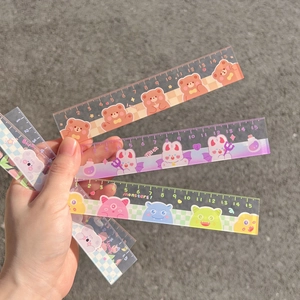 Close-up of cute 15cm plastic rulers with various cartoon patterns held in hand