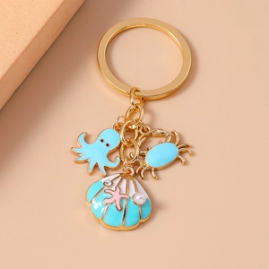Detail of gold keychain with blue enamel octopus, crab, and pearl seashell pendants