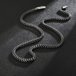 Detailed close-up of a silver titanium steel wheat chain necklace with sharp metallic luster