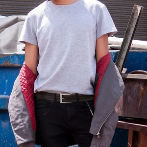 Detail of dark brown leather belt worn with grey jacket and light purple t-shirt