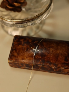 Detailed macro shot of gold cross bracelet with zircon inlay on a vintage wooden box