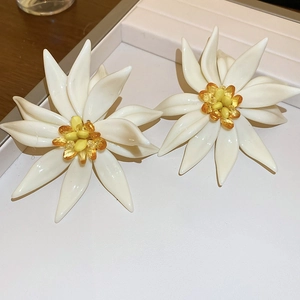 Detail view of white resin flower earrings with yellow beaded centers on display