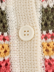 Detailaufnahme von buntem Häkelstrick mit weißem Knopf und gestreiftem Farbmuster