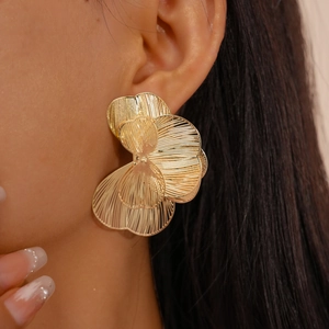 Detailed close-up of a model wearing gold hollow petal earrings with metallic texture