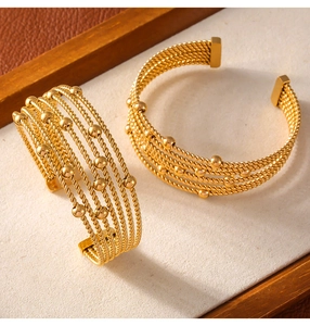 Detail of gold multilayer twisted rope bracelets with bead accents in titanium steel