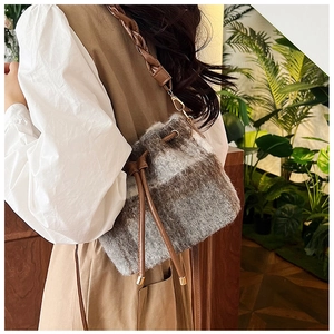 Detail of wool bucket bag with gray brown plaid and drawstring closure on a model