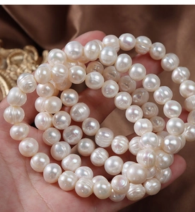 Close-up of natural freshwater pearls held in hand over dark brown silk fabric