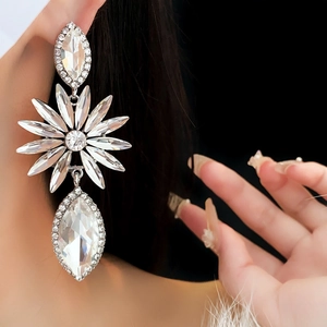Détail macro de grandes boucles d'oreilles fleurs et gouttes avec cristaux brillants