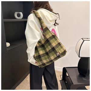 Detail of green and brown checkered plush tote bag shown being worn by a fashion model
