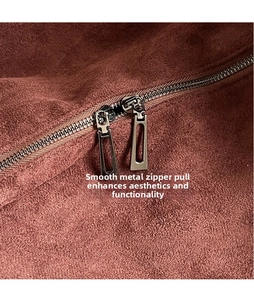 Detail of the gunmetal dual zippers on a brown suede tote bag showing texture