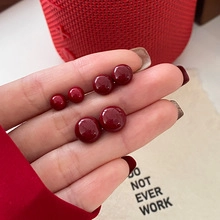 Detailed view of natural red round beads in multiple sizes held in hand on red texture