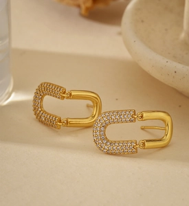 Macro view of gold U-shaped link earrings with pavé zircons and polished finish
