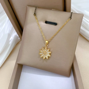 Detail of gold daisy pendant with sparkling crystals resting on white silk fabric