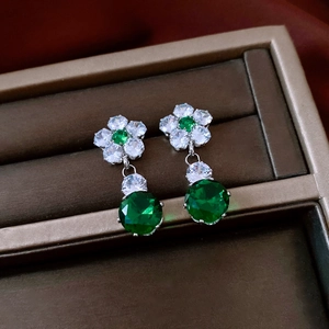 Detailed close-up of vintage flower earrings with green zircon in a premium jewelry box