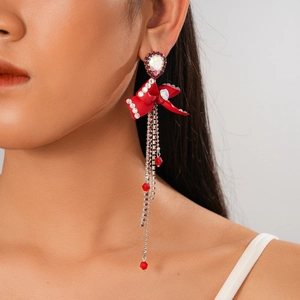 Close-up of red fabric bow earrings with sparkling silver tassel chains and crystals