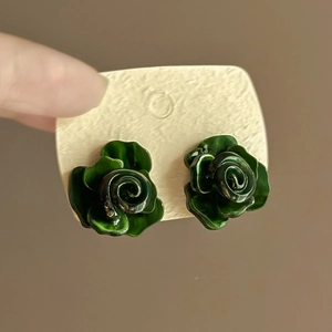 Detailansicht der grünen mehrlagigen Blumenohrstecker auf einer beigen Karte