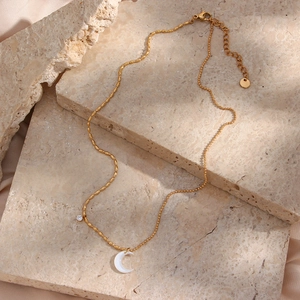 Detail of gold crescent moon necklace featuring unique spliced bead chains and zircon