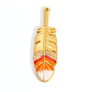 Macro detail of 18K gold plated feather pendant with red enamel and sparkling rhinestones