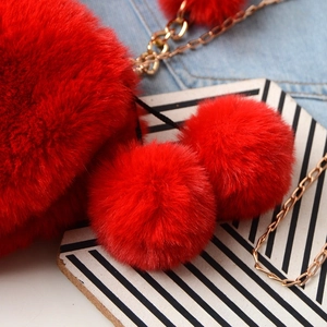 Close-up of vibrant red faux fur handbag featuring soft texture and gold chain strap