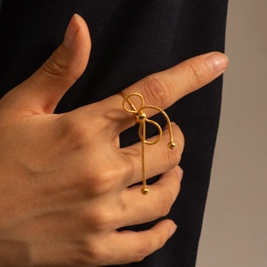 Detail of gold butterfly bow ring with snake chain tassels on hand over black fabric