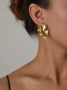 Close-up of golden irregular textured 18K gold plated earring worn by a model