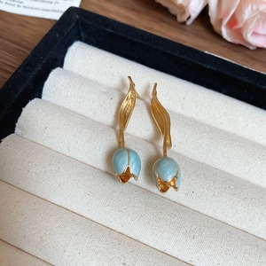 Detailed macro view of vintage tulip earrings in golden metal with light blue enamel finish