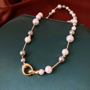 Vue détaillée du collier de perles dorées avec perles grises et fermoir anneau rétro