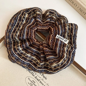 Détail d'un chouchou en tricot rayé rétro avec texture crochet sur un plateau vintage