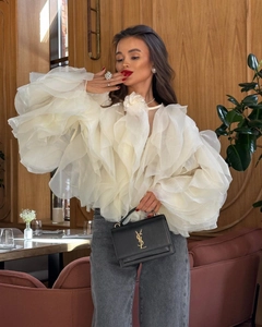 Détail de chemisier blanc en organza à volants avec col fleuri et jean gris délavé