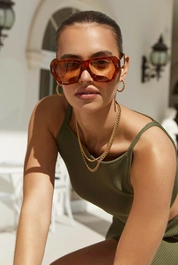 Detail of amber oversized square sunglasses with gold rope earrings and layered necklace