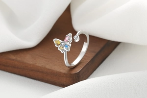 Detail view of butterfly open ring with colorful zircons on a wooden display