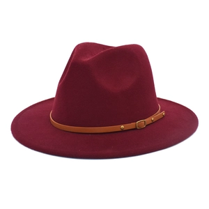 Detail of burgundy wool fedora hat featuring a brown leather belt strap and gold metal studs