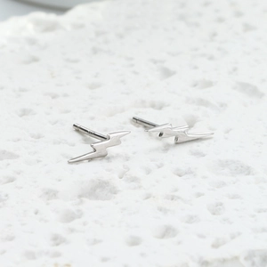Macro view of minimalist s925 silver lightning bolt stud earrings on stone background
