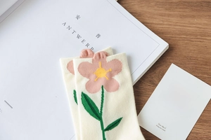 Detail of cotton crew socks with pink tulip floral patterns on a wooden table background