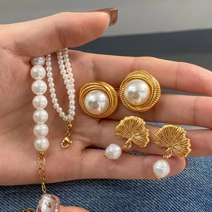 Retro pearl jewelry set with necklace, bracelet and golden floral earrings on denim