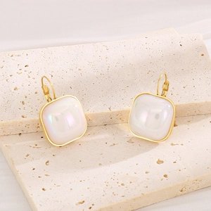 Gros plan de boucles d'oreilles vintage dorées avec perles carrées aux reflets nacrés